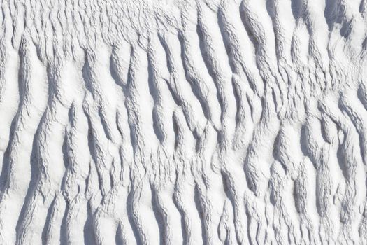 Ribbed abstract texture of Pamukkale calcium travertine in Turkey, asymmetric pattern close-up.