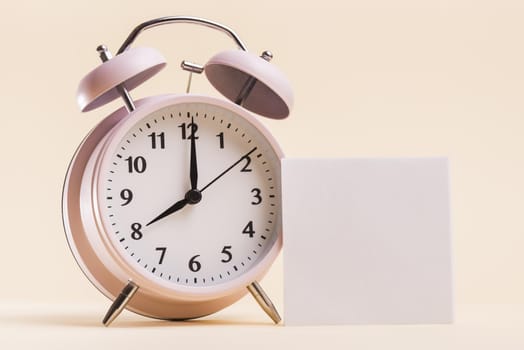 pink alarm clock with blank white adhesive note beige background. Resolution and high quality beautiful photo