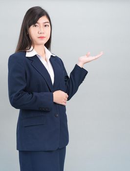 Asian woman in suit open hand palm gestures with empty space isolated on gray background