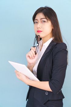 Young Asain women in suit standing using her digital tablet against blue background