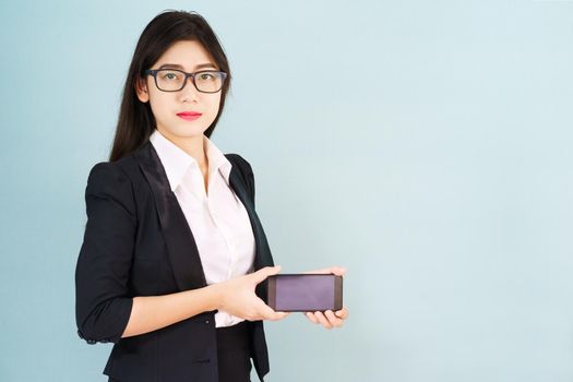 Young women in suit holding her smartphone standing against blue background