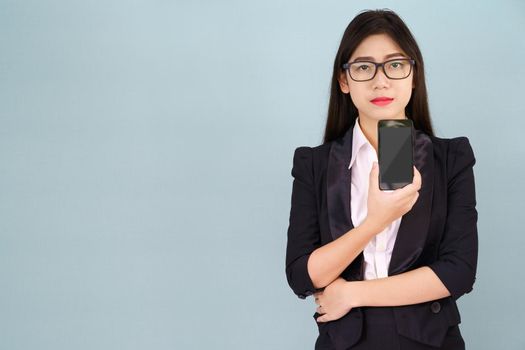 Young women in suit holding her smartphone standing against blue background