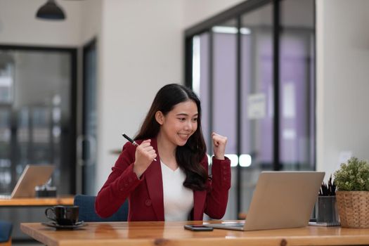 Portrait of success businesswoman enjoy success with laptop on work desk. Authentic shot joyful woman got jackpot, Surprised and celebrating her victory.