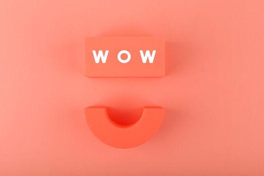 Wow inscription and happy smile symbol on orange background. Colored minimal wow concept of expressing emotions and being excited