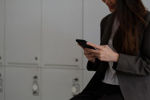 Cheerful working woman using mobile phone smiling with pleasure as she reads a text message in office.