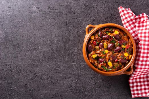Traditional mexican tex mex chili con carne in a bowl on black slate background