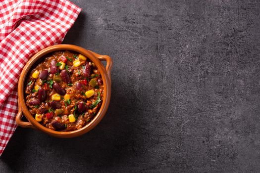 Traditional mexican tex mex chili con carne in a bowl on black background.