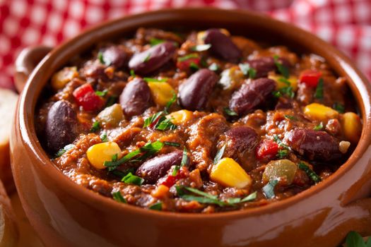 Traditional mexican tex mex chili con carne in a bowl on black background.