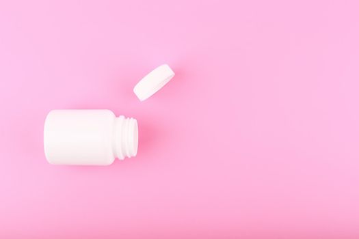 Minimal flat lay with white opened medication bottle on saturated pinkish purple bright background with copy space. Concept of vitamins or supplements