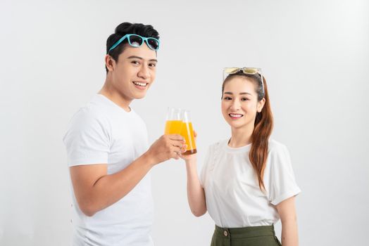 A young couple drink OJ on white background