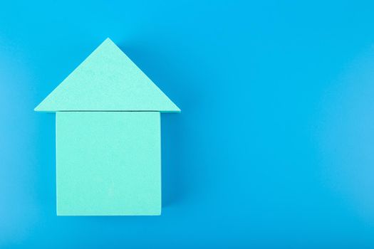 Mortgage, loan or saving money for home and investing in real estate trendy concept. Bright aqua blue toy house on blue background with copy space