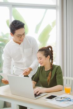 Wide shot of nice man and woman surfing in laptop while sitting at table