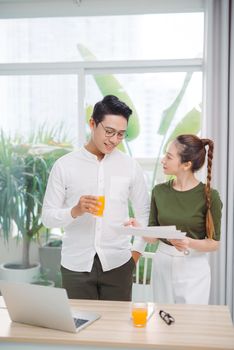 Young couple discussing things looking at laptop while having orange juice in stylish bright room