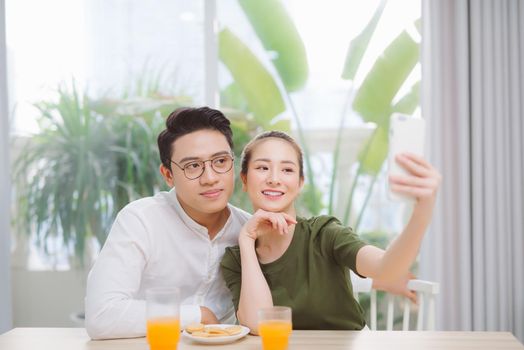 Affectionate couple making selfie in the morning. Drinking orange juice in house