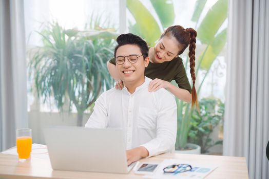 Wide shot of gorgeous lady and sir surfing in laptop while sitting at table