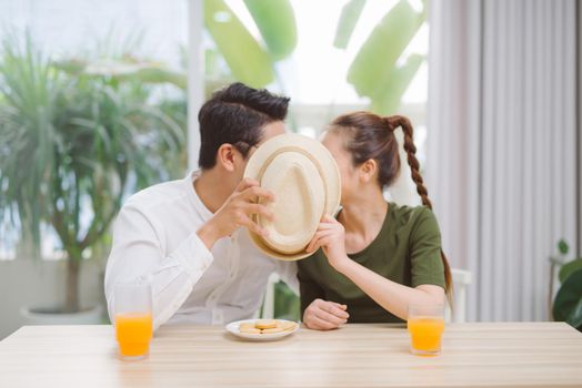 Couple kissing, hiding behind hat, love background