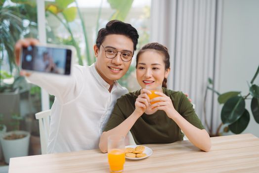 Smiling young couple taking selfie in the morning at home.