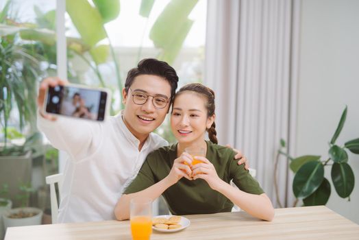 Beautiful young couple making selfie ,using a smart phone and smiling while sitting in their apartment
