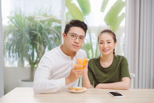 Loving man and woman drinking fresh orange juice enjoying pleasant morning cooking together, healthy meal and lifestyle concept