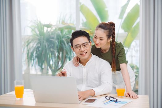 Book online. Happy attractive woman hugging man while he using laptop
