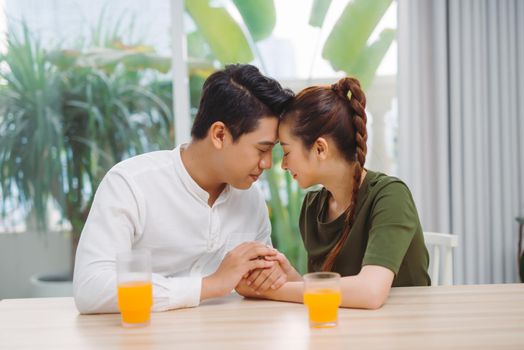 Happy young couple on a date drinking coffee and holding hands in cafe