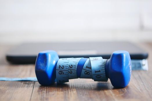Fitness concept with dumbbell, measurement tape and weight scale on floor .