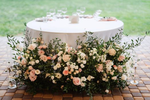 The presidium of the newlyweds in the banquet hall of the restaurant is decorated with candles and green plants, wisteria hangs from the ceiling