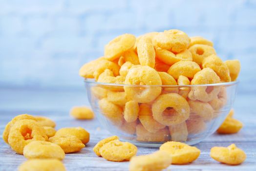 puffed corn rings chips in black bowl on white background,