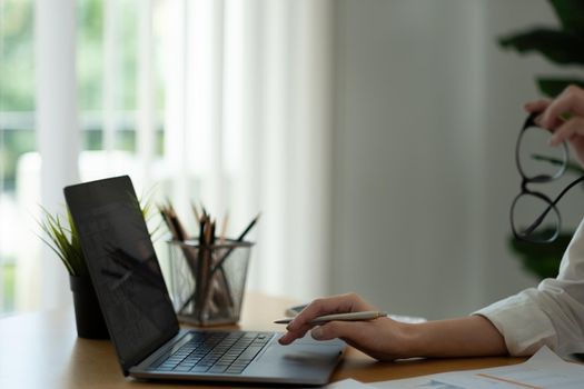 Businesswoman using laptop computer for analysis maketing plan, Accountant calculate financial report, computer with graph chart. Business, Finance and Accounting concept.