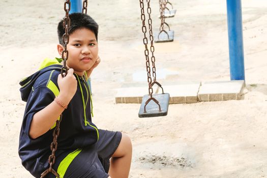 Happy asian sport boy play on swing playground in Garden