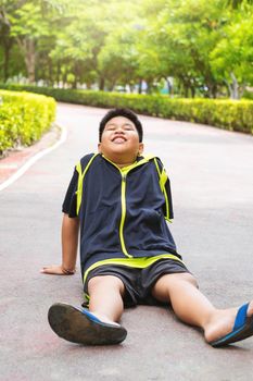 Selective focus at young Asian boy sit and tired on track after running