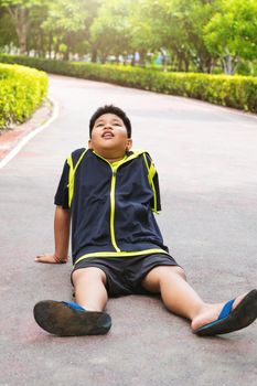 Selective focus at young Asian boy sit and tired on track after running