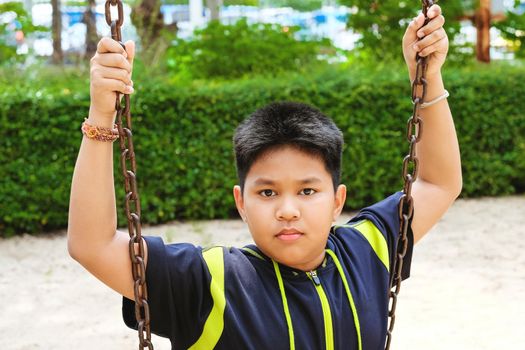 Happy asian sport boy play on swing playground in Garden