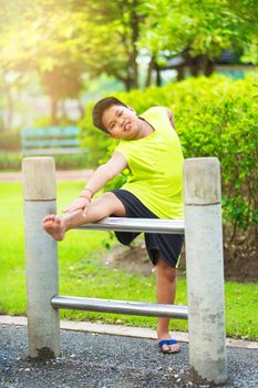 Asian sport boy stretching on iron bar in garden.