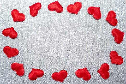 red hearts laid out in the shape of an oval on a silver background, with copy space