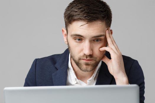 Business Concept - Portrait handsome serious business man in suit looking at laptop. White Background.