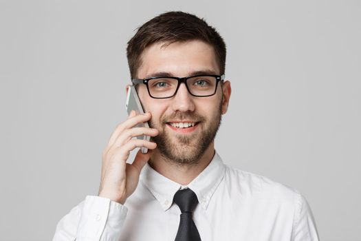 Business Concept - Portrait young handsome cheerful business man in suit talking on phone looking at camera. White background. Copy Space.