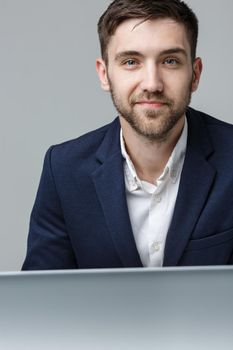 Business Concept - Portrait handsome serious business man in suit looking at work in laptop. White Background.