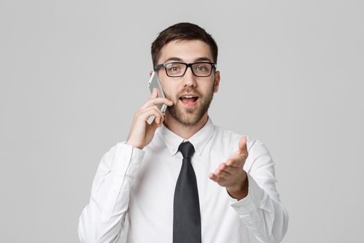 Business Concept - Portrait young handsome angry business man in suit talking on phone looking at camera. White background.