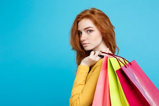 Shopping Concept - Close up Portrait young beautiful attractive redhair girl looking at camera. Blue Pastel Background. Copy space.