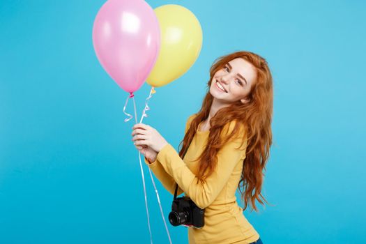 Lifestyle and Party concept - Close up Portrait young beautiful attractive ginger red hair girl with colorful balloon and vintage camera. Blue Pastel Background. Copy space.