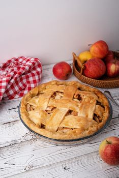 Autumn foods. Top view of homemade apple pie on white wooden table, decorated with apples, sugar and tablecloth