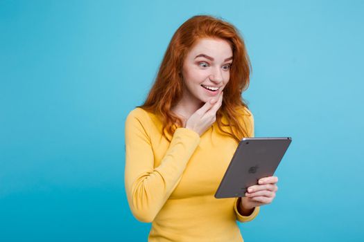 People and Technology Concept - Close up Portrait young beautiful attractive redhair girl happy smiling on digital table with wining something. Blue Pastel Background. Copy space.