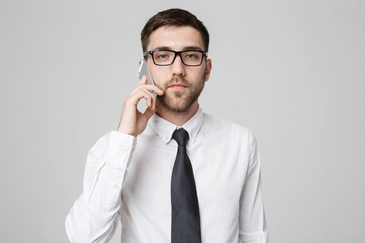 Business Concept - Portrait young handsome angry business man in suit talking on phone looking at camera. White background.