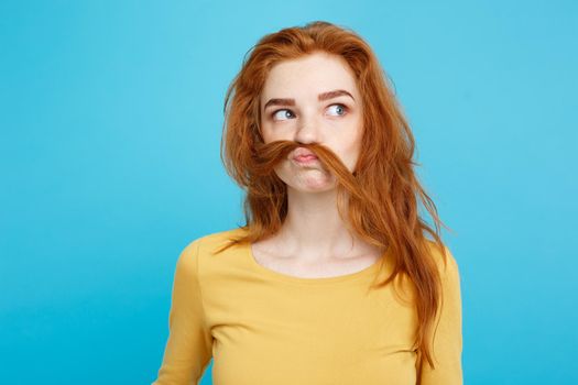 Headshot Portrait of happy ginger red hair girl imitating to be man with hair fake mustache.Pastel blue background. Copy Space.