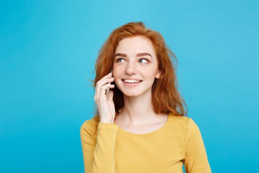 Lifestyle and Technology concept - Portrait of cheerful happy ginger red hair girl with joyful and exciting talking with friend by mobile phone. Isolated on Blue Pastel Background. Copy space.