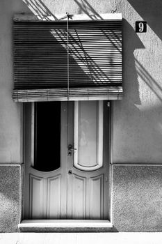 Novelda, Alicante, Spain- September 18, 2021: Old wooden door and typical spanish wooden blind in Spain. Monochrome picture.