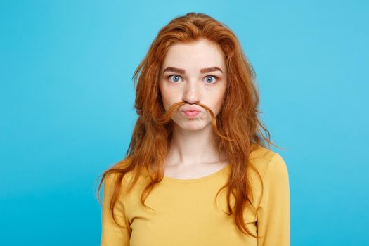 Headshot Portrait of happy ginger red hair girl imitating to be man with hair fake mustache.Pastel blue background. Copy Space.