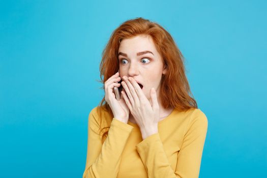 Lifestyle concept - Portrait of ginger red hair girl with shocking and stressful expression while talking with friend by mobile phone. Isolated on Blue Pastel Background. Copy space.