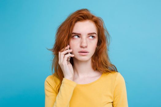 Lifestyle concept - Portrait of ginger red hair girl with shocking and stressful expression while talking with friend by mobile phone. Isolated on Blue Pastel Background. Copy space.